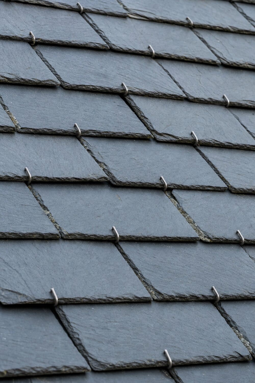 Détail d'un rang d'ardoises fixées au crochet, recouvrement visible