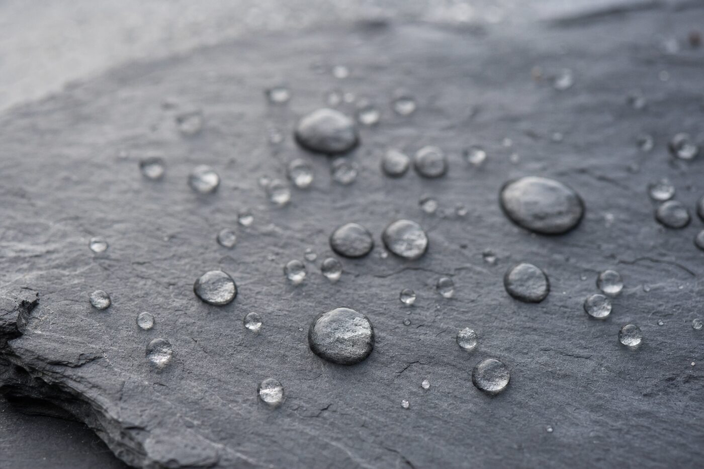 Gouttes d'eau perlant sur une ardoise traitée à l'hydrofuge